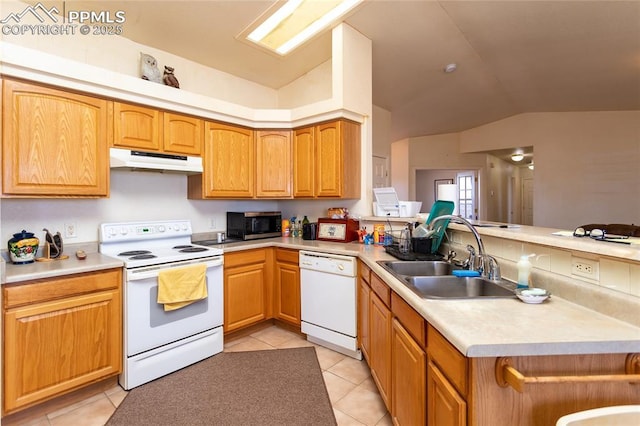 kitchen featuring light tile patterned floors, white appliances, a peninsula, under cabinet range hood, and a sink