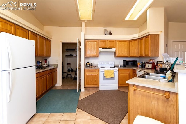 kitchen featuring white appliances, light tile patterned floors, under cabinet range hood, brown cabinetry, and a sink