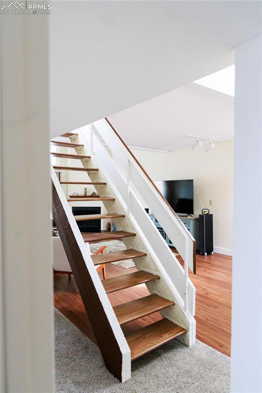 stairway with track lighting, baseboards, and wood finished floors