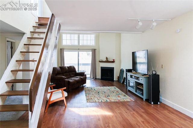 living room with stairs, a fireplace, wood finished floors, and track lighting
