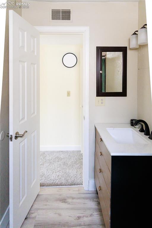 bathroom with baseboards, visible vents, wood finished floors, and vanity