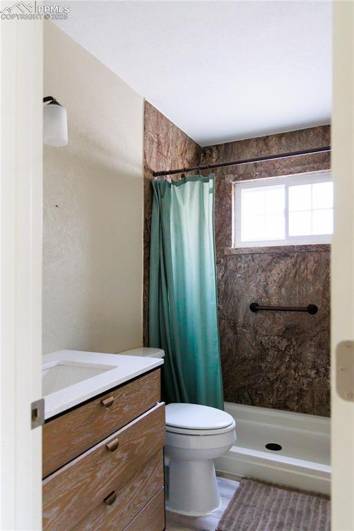 full bath featuring a stall shower, toilet, and vanity