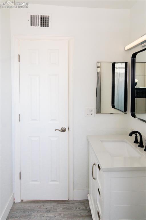 bathroom with wood finished floors, vanity, baseboards, and visible vents