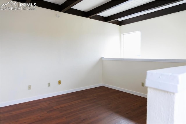 spare room with beam ceiling, baseboards, and wood finished floors