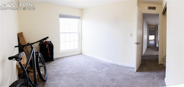 hallway with carpet floors, baseboards, and visible vents
