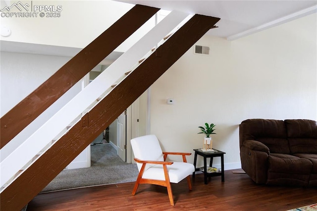 living area featuring baseboards, visible vents, wood finished floors, and stairway