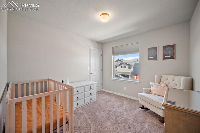 bedroom with light colored carpet, baseboards, and a nursery area