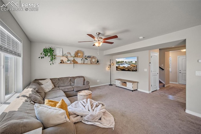 living area with carpet floors, a ceiling fan, baseboards, and stairs