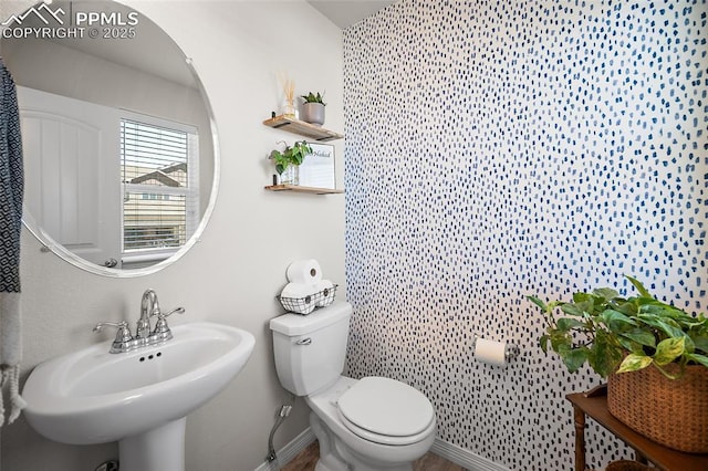 bathroom with toilet, baseboards, and a sink