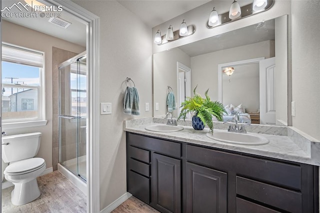 ensuite bathroom with double vanity, toilet, a shower stall, and a sink