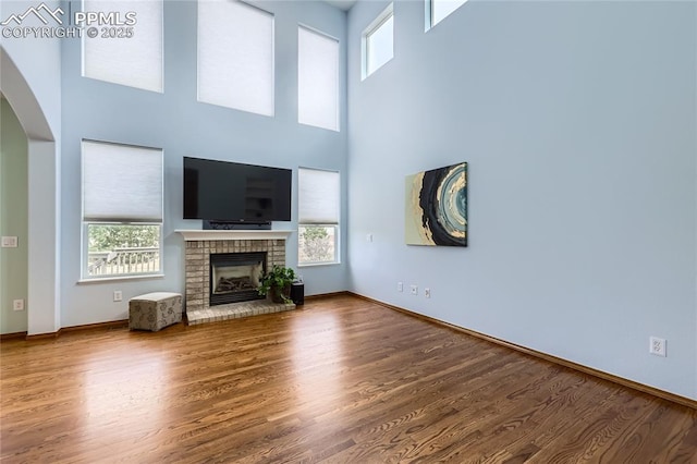 unfurnished living room with a fireplace, wood finished floors, and a healthy amount of sunlight