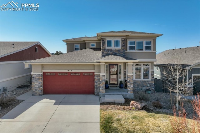 prairie-style house with driveway, stone siding, and an attached garage