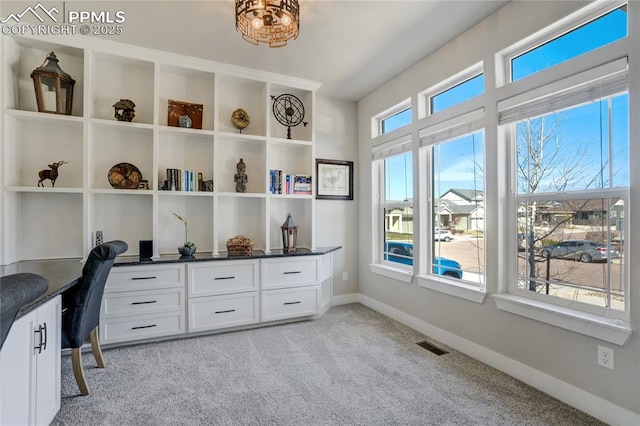 office space with built in desk, light carpet, baseboards, and visible vents