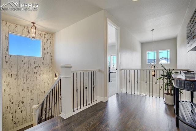 interior space with a chandelier, wood finished floors, baseboards, and an upstairs landing