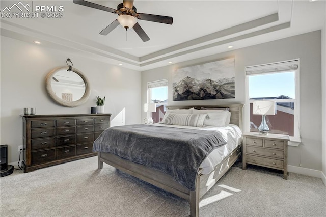 bedroom featuring carpet floors, a raised ceiling, and multiple windows