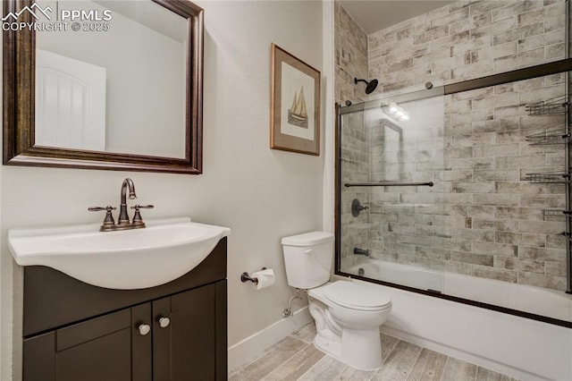 full bathroom with baseboards, bath / shower combo with glass door, toilet, vanity, and wood finished floors
