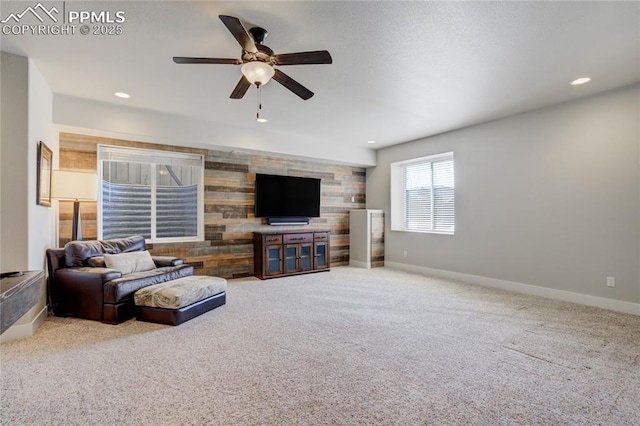 living area featuring ceiling fan, baseboards, and carpet floors