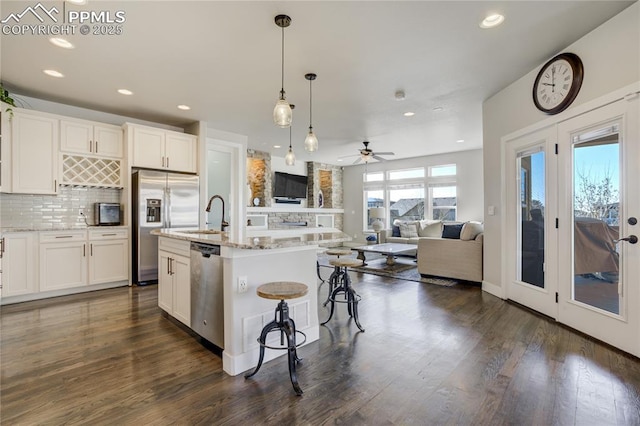kitchen featuring white cabinets, a sink, ceiling fan, stainless steel appliances, and decorative backsplash