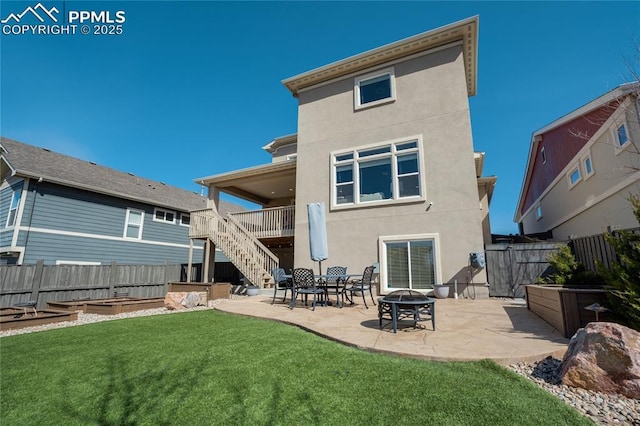back of house featuring a patio area, a vegetable garden, a lawn, fence, and stairs