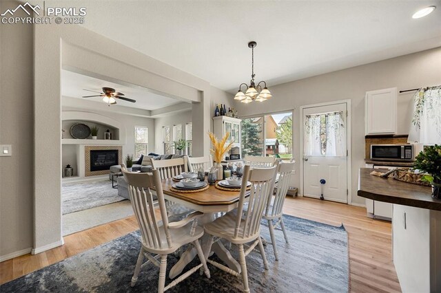 4454 College Park Ct, Colorado Springs, CO 80918 - dining space featuring plenty of natural light, light wood-style floors, ceiling fan, and a glass covered fireplace
