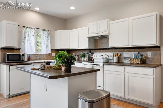 4454 College Park Ct, Colorado Springs, CO 80918 - kitchen featuring white appliances, white cabinetry, under cabinet range hood, and decorative backsplash