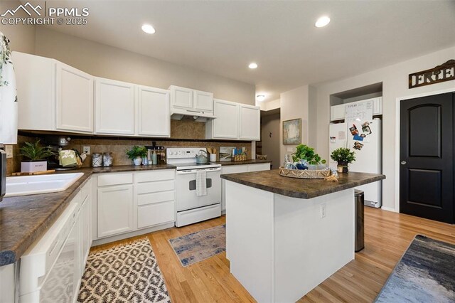 4454 College Park Ct, Colorado Springs, CO 80918 - kitchen featuring white appliances, dark countertops, a kitchen island, under cabinet range hood, and light wood-type flooring