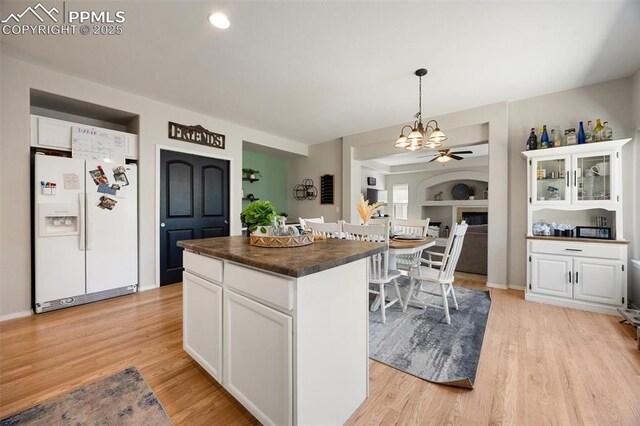4454 College Park Ct, Colorado Springs, CO 80918 - kitchen with dark countertops, light wood-style floors, white cabinets, a notable chandelier, and white fridge with ice dispenser