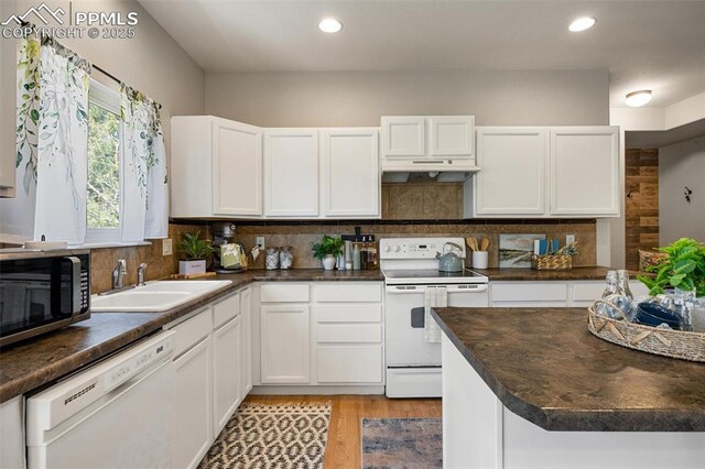 4454 College Park Ct, Colorado Springs, CO 80918 - kitchen featuring white appliances, under cabinet range hood, backsplash, a sink, and dark countertops