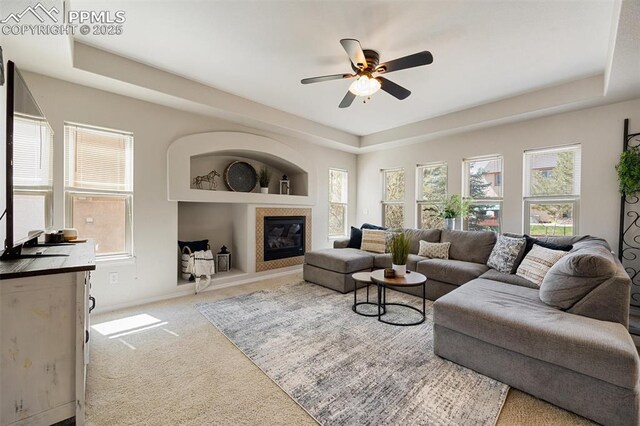 4454 College Park Ct, Colorado Springs, CO 80918 - carpeted living area with a tiled fireplace, ceiling fan, and a raised ceiling