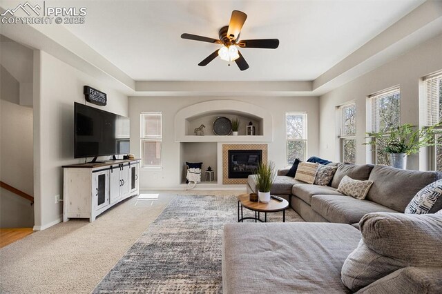 4454 College Park Ct, Colorado Springs, CO 80918 - living area with light colored carpet, baseboards, a tiled fireplace, a ceiling fan, and built in features