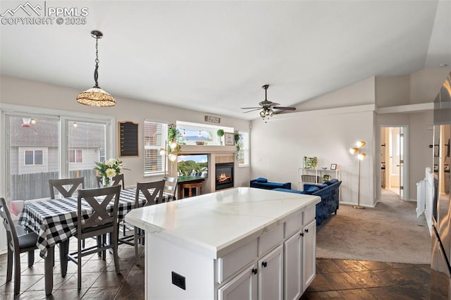 kitchen with a center island, a ceiling fan, hanging light fixtures, a tile fireplace, and white cabinetry