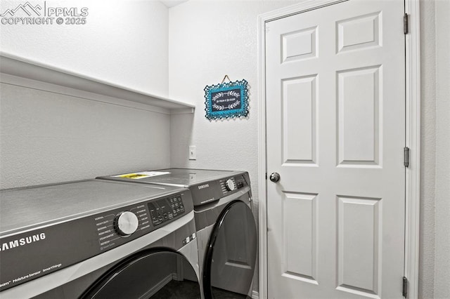 washroom with a textured wall, washer and clothes dryer, and laundry area