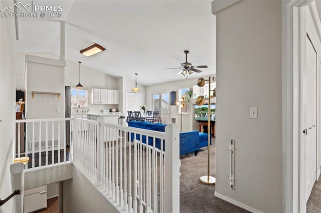 hallway with dark carpet, lofted ceiling, and plenty of natural light