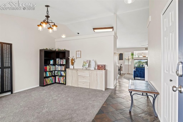 foyer with lofted ceiling, a notable chandelier, stone finish floor, and baseboards