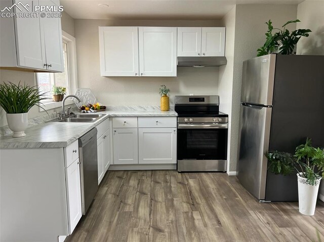 131 Hayes Dr, Colorado Springs, CO 80911 - kitchen with under cabinet range hood, light countertops, wood finished floors, a sink, and appliances with stainless steel finishes
