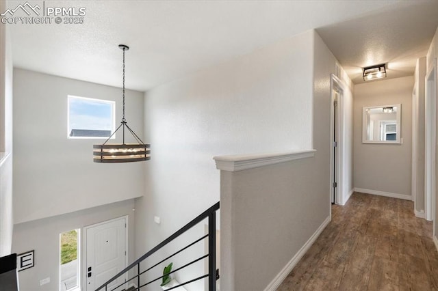 13424 Stone Valley Dr, Peyton, CO 80831 - corridor with baseboards, an upstairs landing, an inviting chandelier, and wood finished floors