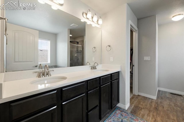 13424 Stone Valley Dr, Peyton, CO 80831 - bathroom with a shower stall, double vanity, a sink, and wood finished floors