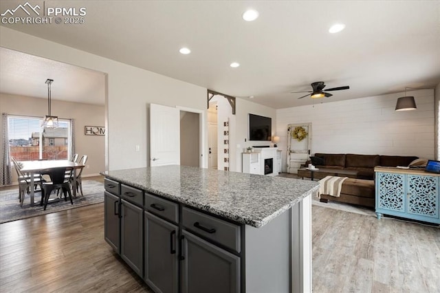 13424 Stone Valley Dr, Peyton, CO 80831 - kitchen featuring a fireplace, light wood-style floors, a center island, and ceiling fan