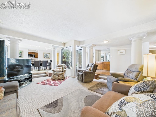 carpeted living room with ornate columns, a textured ceiling, and baseboards