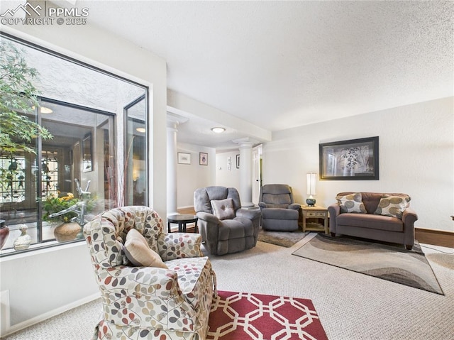 living room with decorative columns, carpet flooring, plenty of natural light, and a textured ceiling