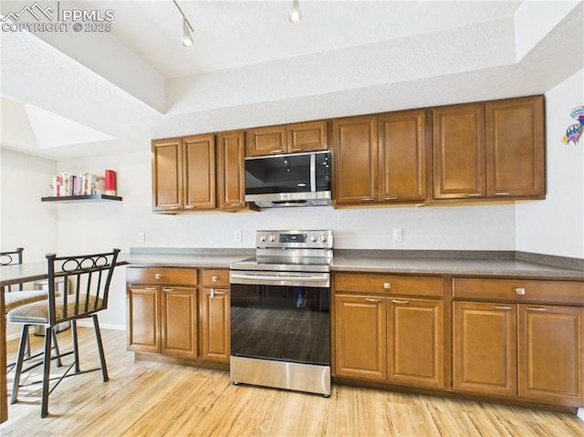 kitchen featuring appliances with stainless steel finishes, brown cabinetry, and light wood finished floors