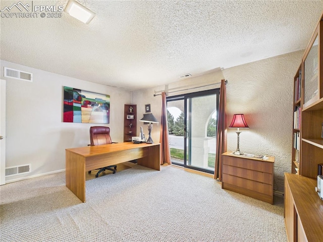office area with light carpet, visible vents, a textured wall, and a textured ceiling