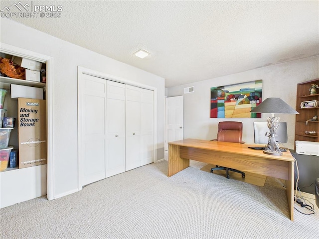 office with carpet flooring, a textured ceiling, and visible vents
