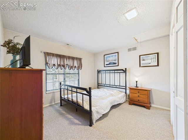 carpeted bedroom with baseboards, attic access, a textured ceiling, and visible vents