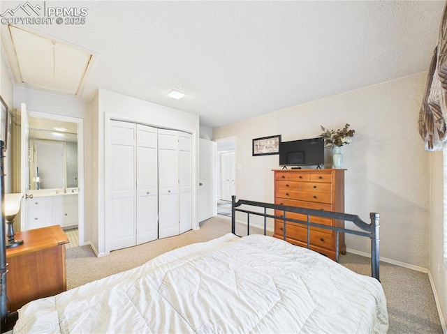 carpeted bedroom with connected bathroom, a closet, a sink, attic access, and baseboards