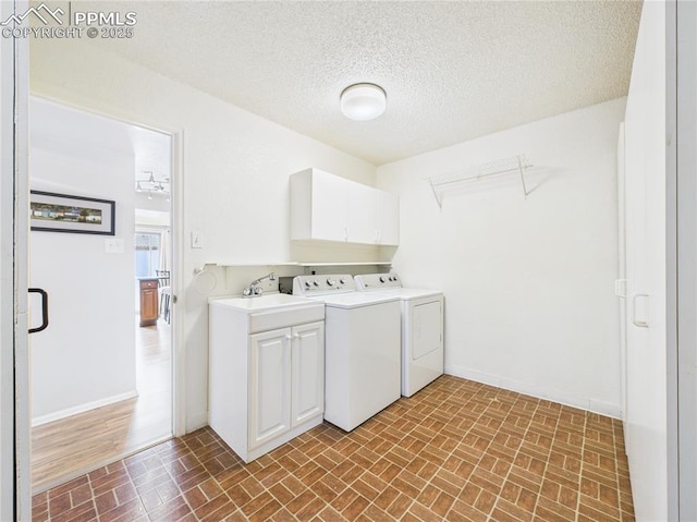 laundry area featuring washing machine and clothes dryer, cabinet space, brick patterned floor, and baseboards