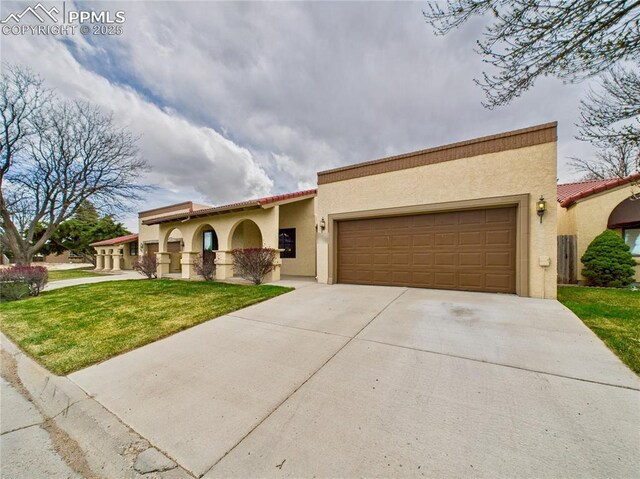 mediterranean / spanish house with stucco siding, a tile roof, a garage, and driveway