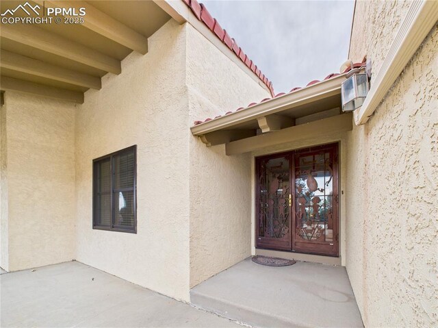 entrance to property featuring stucco siding and a tiled roof