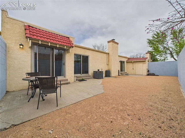 rear view of house featuring cooling unit, stucco siding, a tiled roof, entry steps, and fence private yard