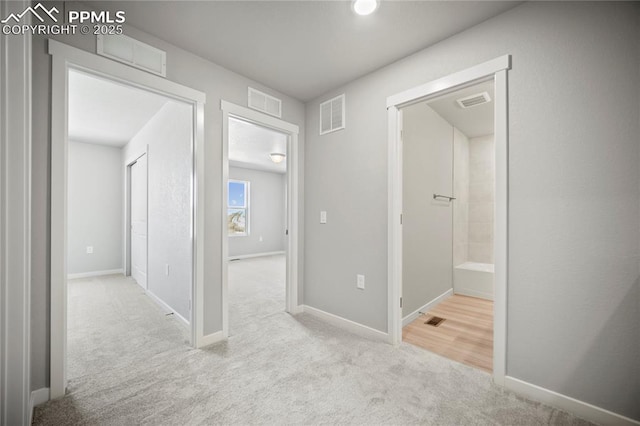 hall featuring baseboards, visible vents, and carpet